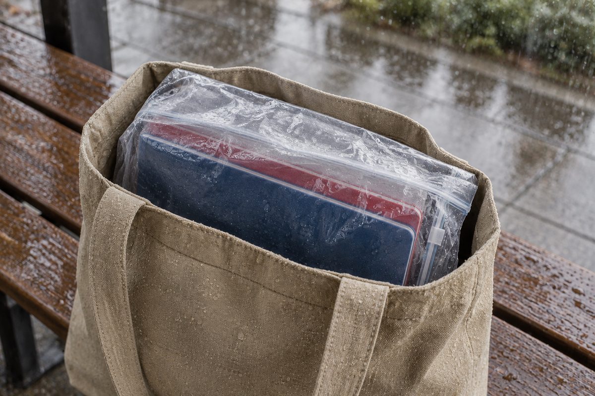 Cabas de cours ouvert avec une doublure plastique repliée sur les cahiers sous la pluie